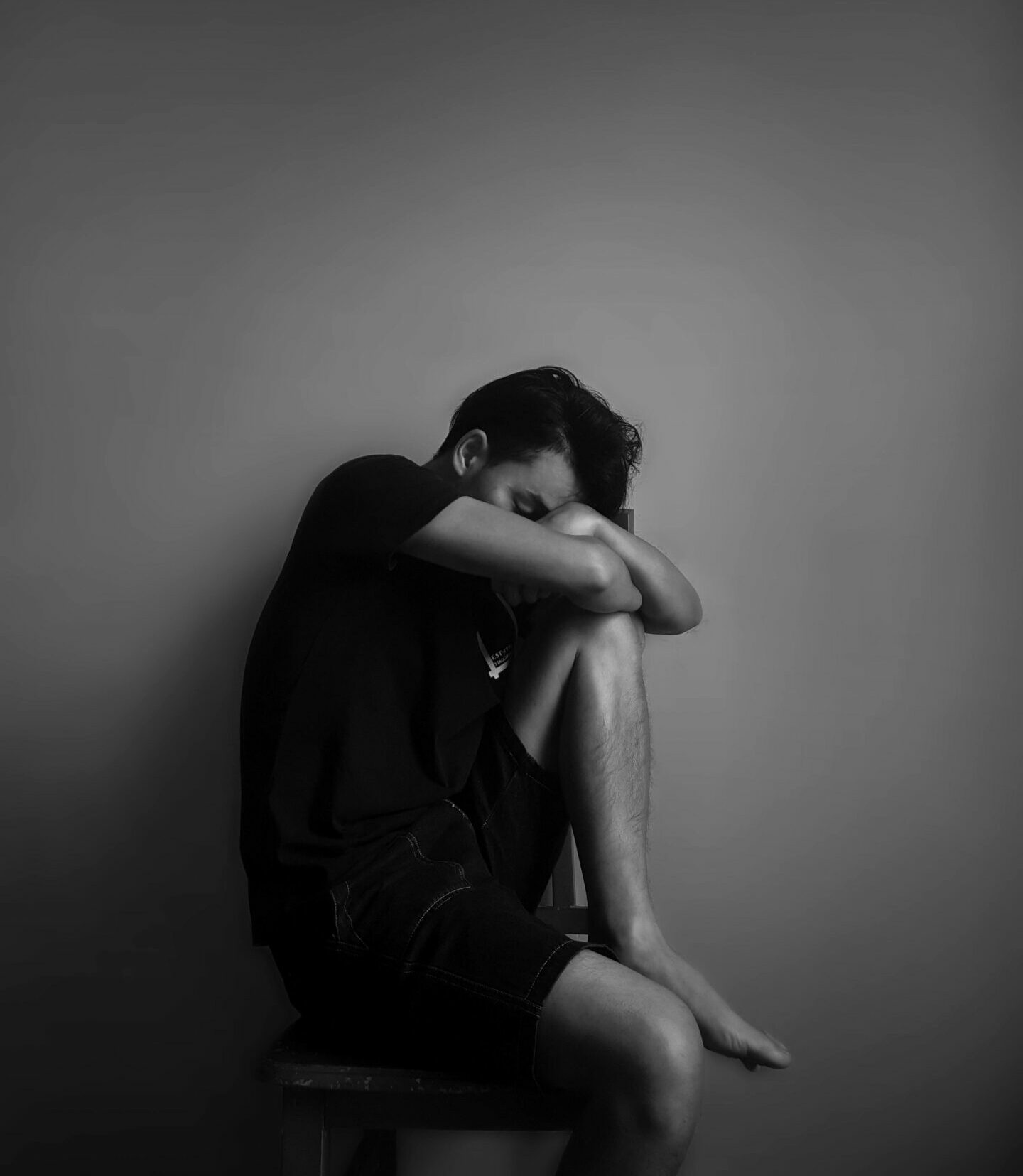 A black and white portrait of a man sitting alone, evoking emotion and contemplation.